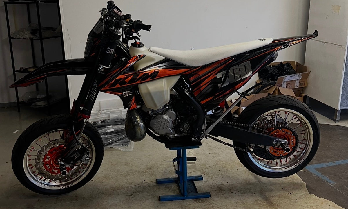 Sturdy Racing supermoto wheels on a KTM 300, side view – silver rim, orange hub