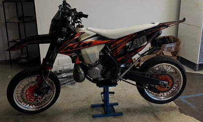 Sturdy Racing supermoto wheels on a KTM 300, side view – silver rim, orange hub